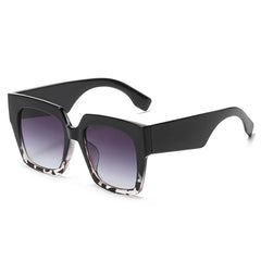 Oversized square sunglasses with blue tortoiseshell gradient lens detail and bold frame material close-up.