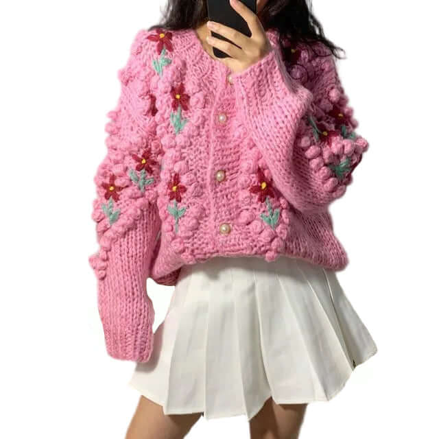 Pink knitted floral cardigan with white skirt, featuring a textured design and embroidered flowers.
